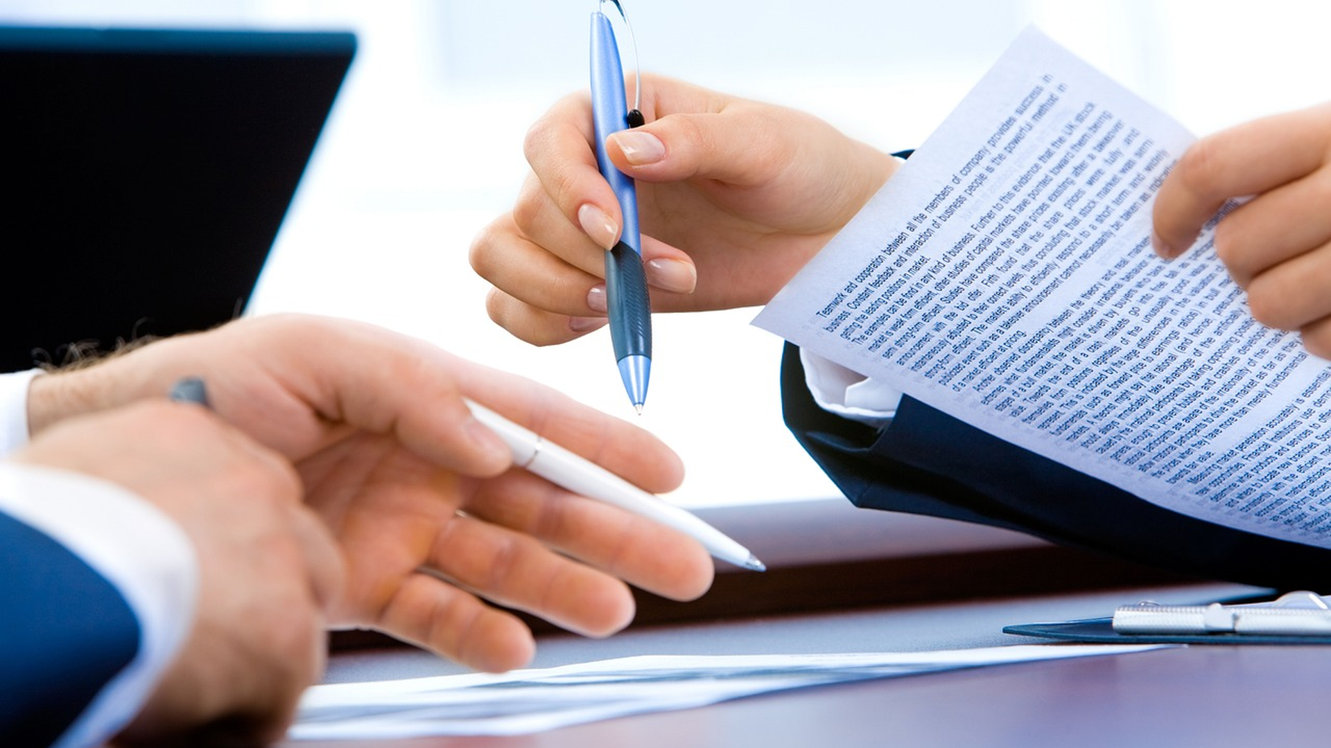 Two people reviewing pre-approval paperwork and exchanging a pen across a desk