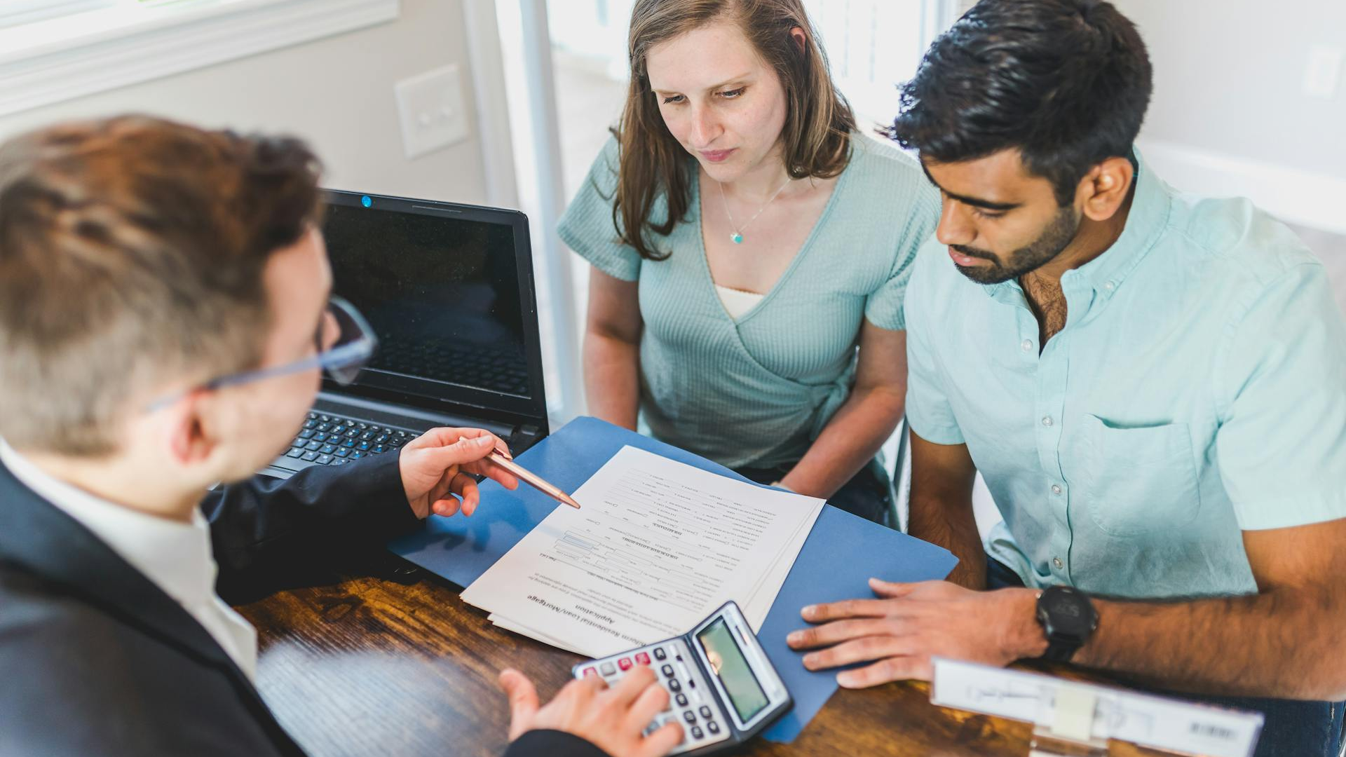 Couple reviewing mortgage documents with a loan officer at a desk