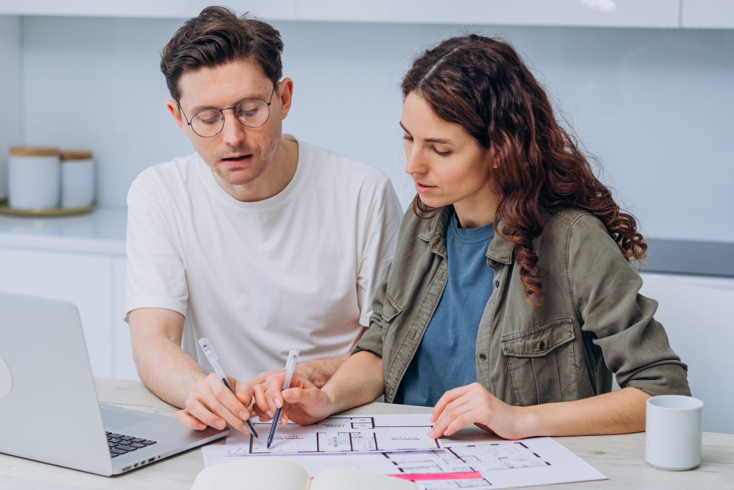 Couple at a kitchen table reviewing a property floor plan with notes, the moment many buyers also check whether their address qualifies for a USDA home loan.