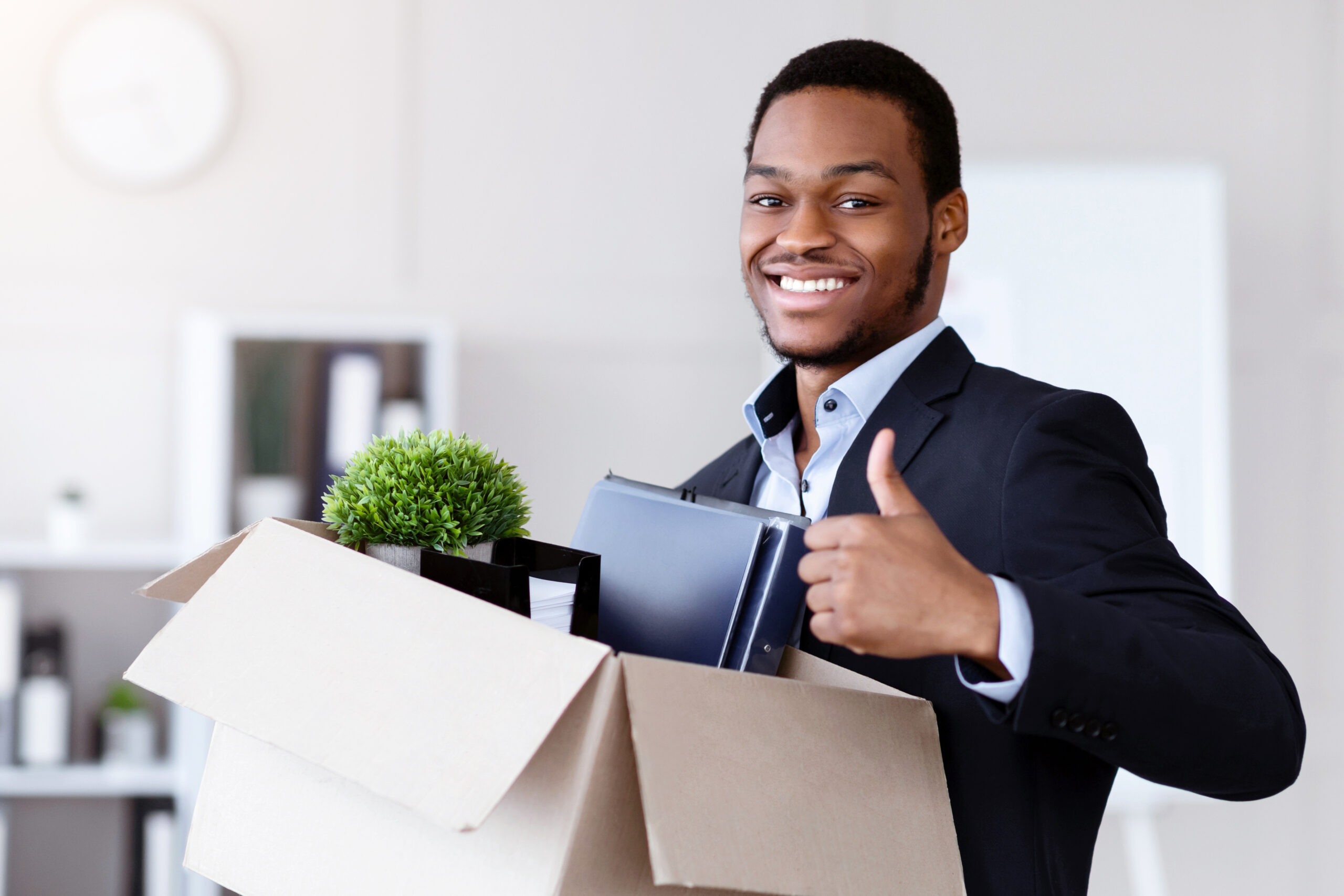 Professional moving to new office with personal belongings, indicating a positive job change