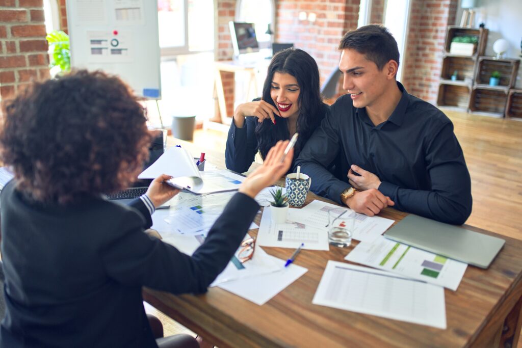 Young couple reviewing mortgage paperwork with a loan officer at a meeting table