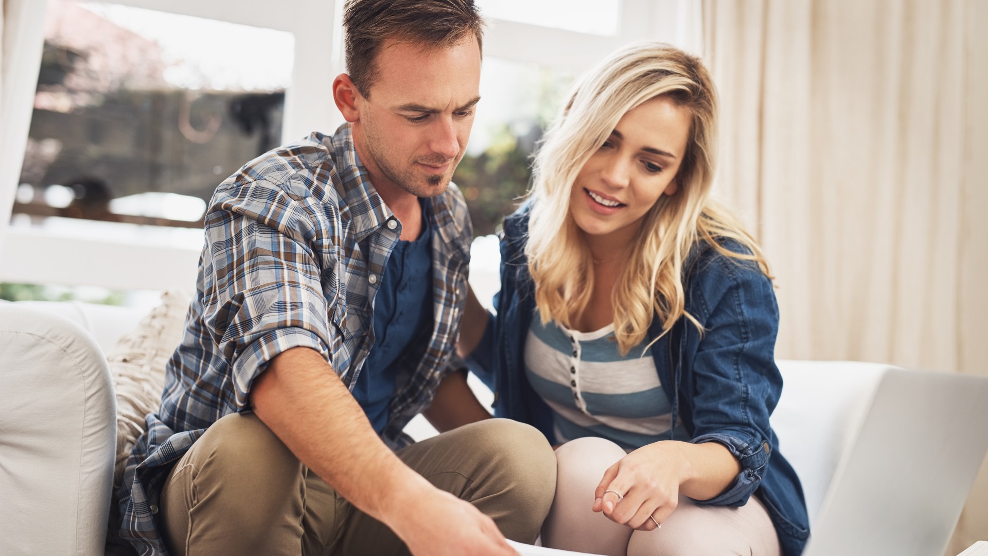Couple reviewing credit score and mortgage paperwork on a laptop at a kitchen table