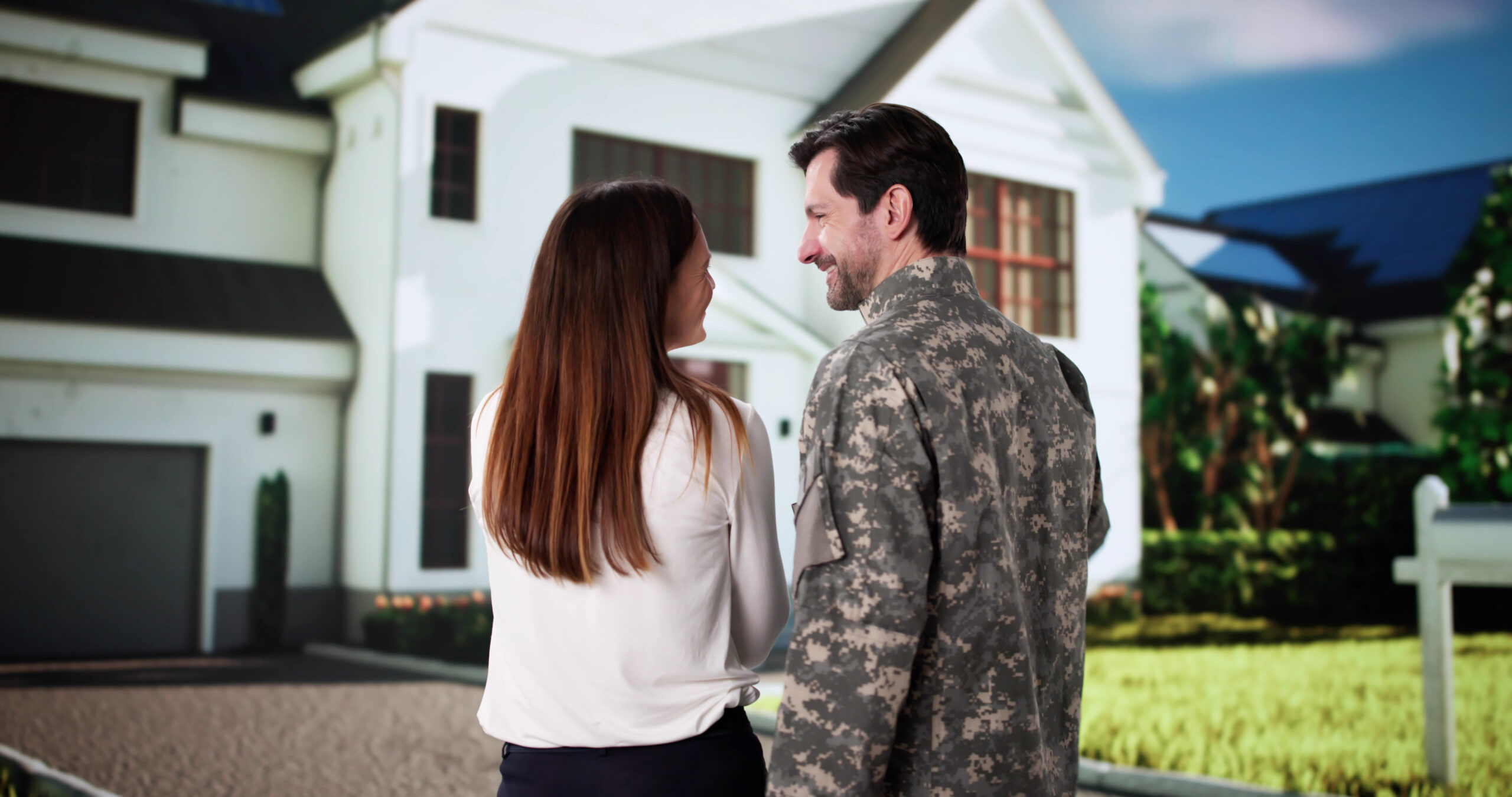 Retired military couple standing in front of their newly purchased American suburban home