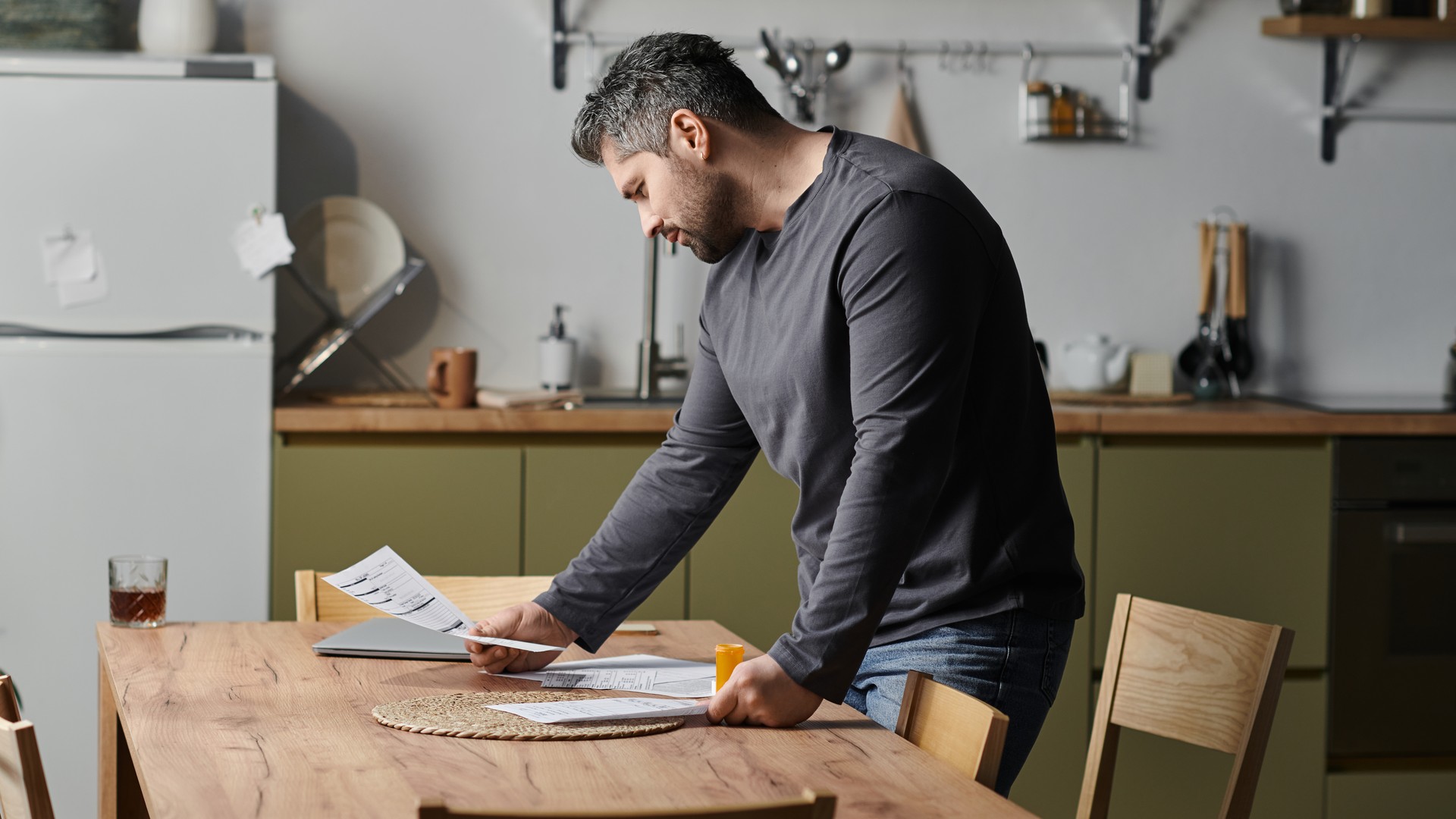 Homeowner comparing a contractor's repair estimate against refinance paperwork at a kitchen table
