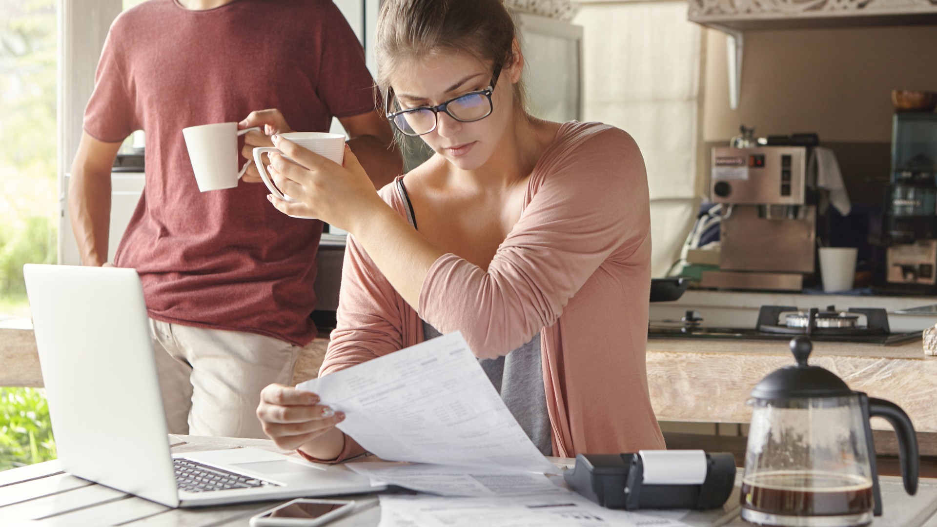 Home image by Fellowship Home Loans Homeowner at a kitchen table comparing a refinance offer letter against a current mortgage statement